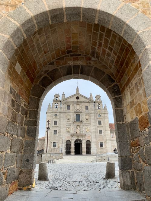 Free Stunning view of a historical church framed by a stone archway in Avila, Spain. Stock Photo