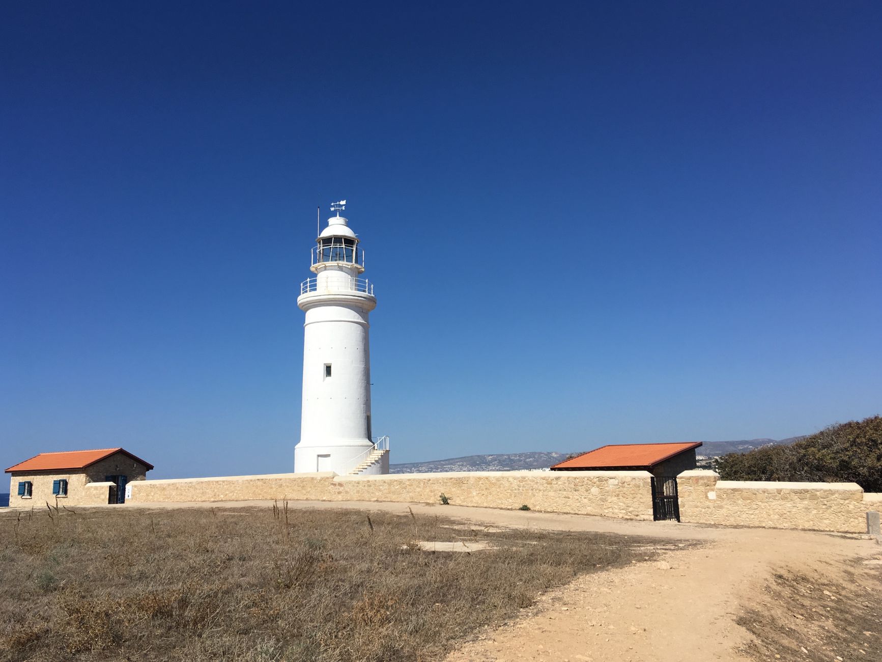 The iconic Paphos Lighthouse stands under a clear blue sky in Cyprus.