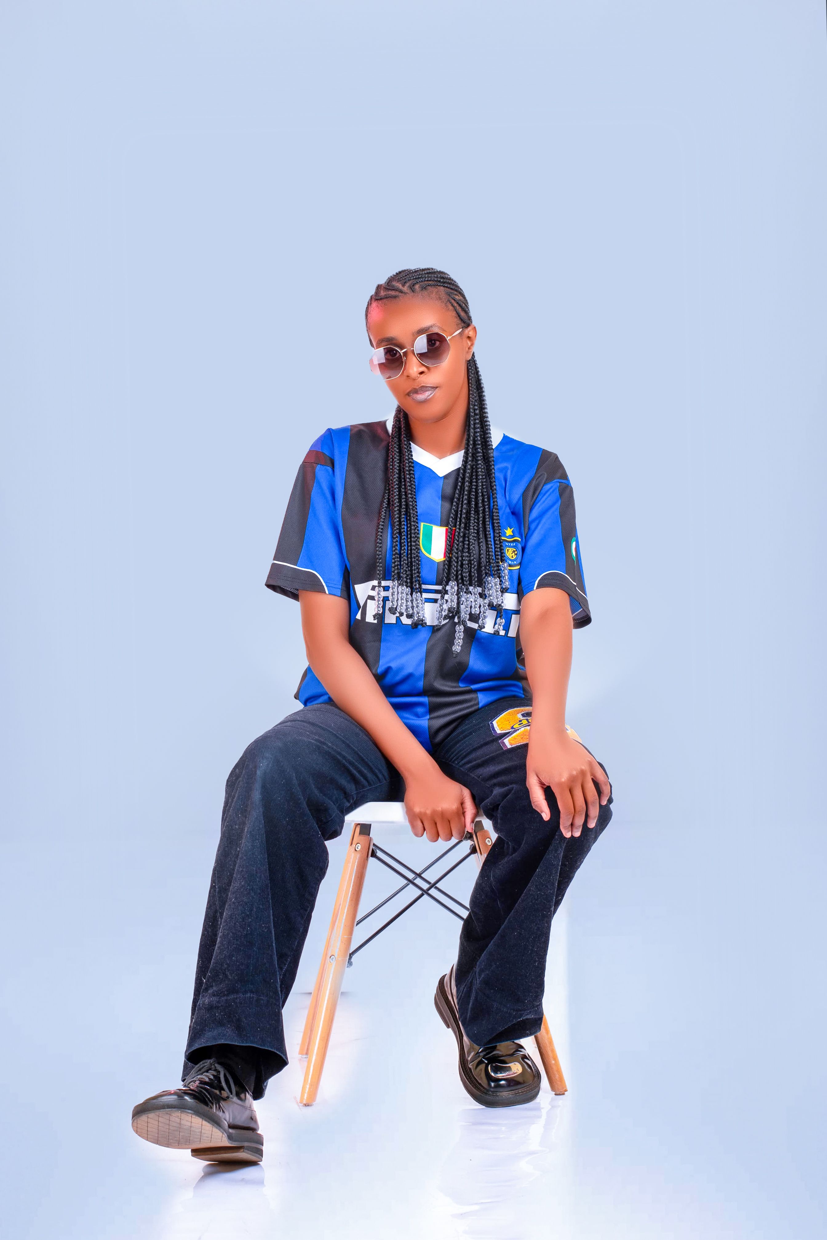 Fashion-forward young woman in a blue sports jersey and jeans striking a cool pose.