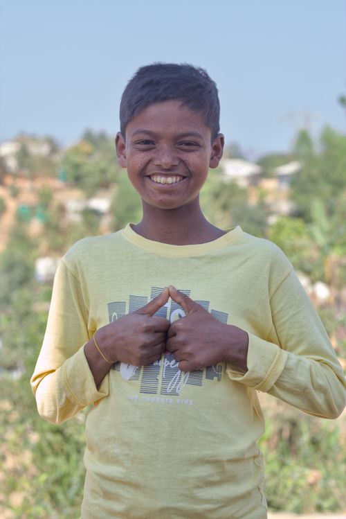 Free A cheerful boy outdoors in a yellow shirt, embodying joy and positivity in a rural setting. Stock Photo