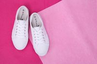 White low-top sneakers on a pink paper backdrop — photo by Thang Nguyen on Pexels