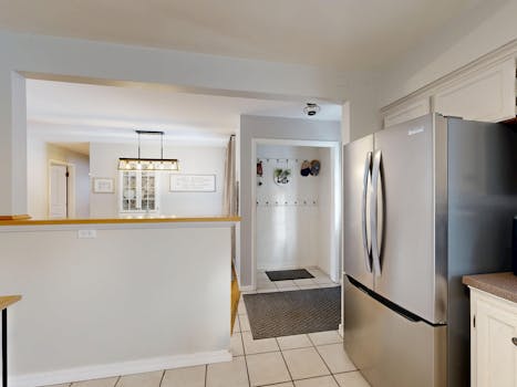 Spacious kitchen with modern design, stainless steel fridge, and elegant lighting.