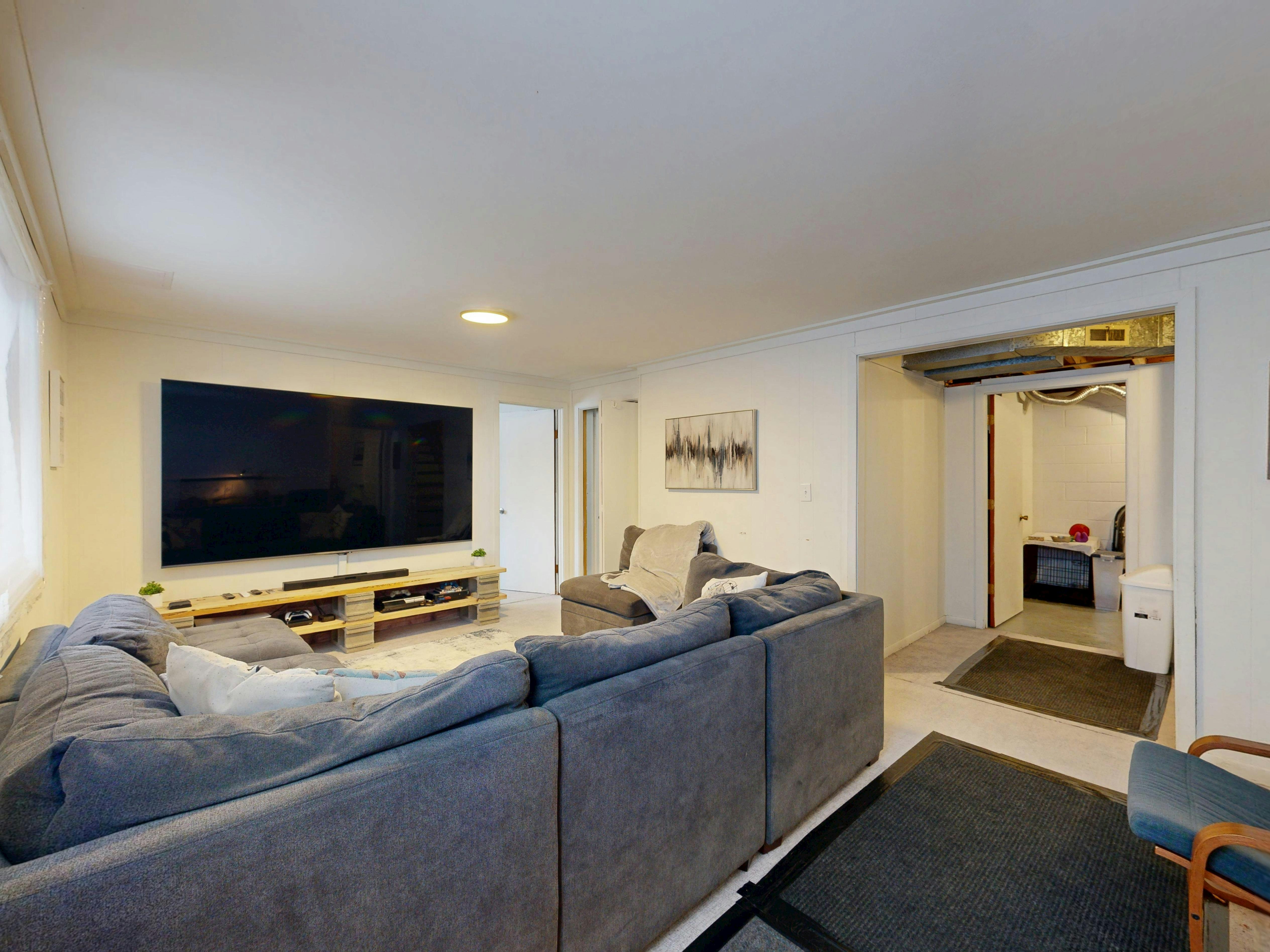 Modern basement living room with large TV, comfortable sofa, and stylish decor.