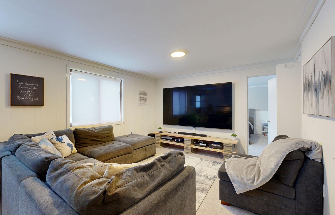 Spacious living room featuring a large flat-screen TV, gray sectional sofa, and cozy decor.