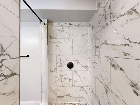 Luxurious modern shower with white and gray marble tiles and minimal design.