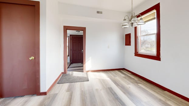 Spacious empty room with modern flooring and natural light through a large window, ideal for real estate listings.