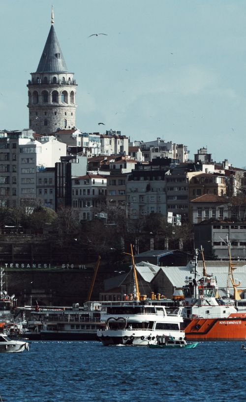 Free Galata Tower rises above the bustling harbor in Istanbul, Türkiye, showcasing historic architecture. Stock Photo