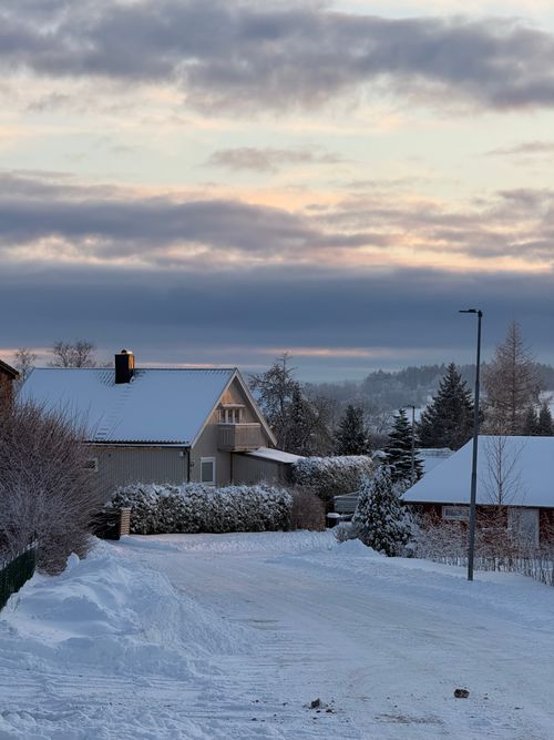 Free A tranquil winter village covered in snow during sunrise. Stock Photo