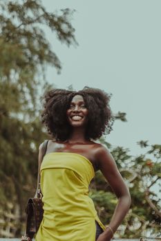 Cheerful woman in a vibrant yellow dress enjoying outdoors on a sunny day.