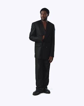 Elegant black man in a formal black suit, posing confidently against a white background.