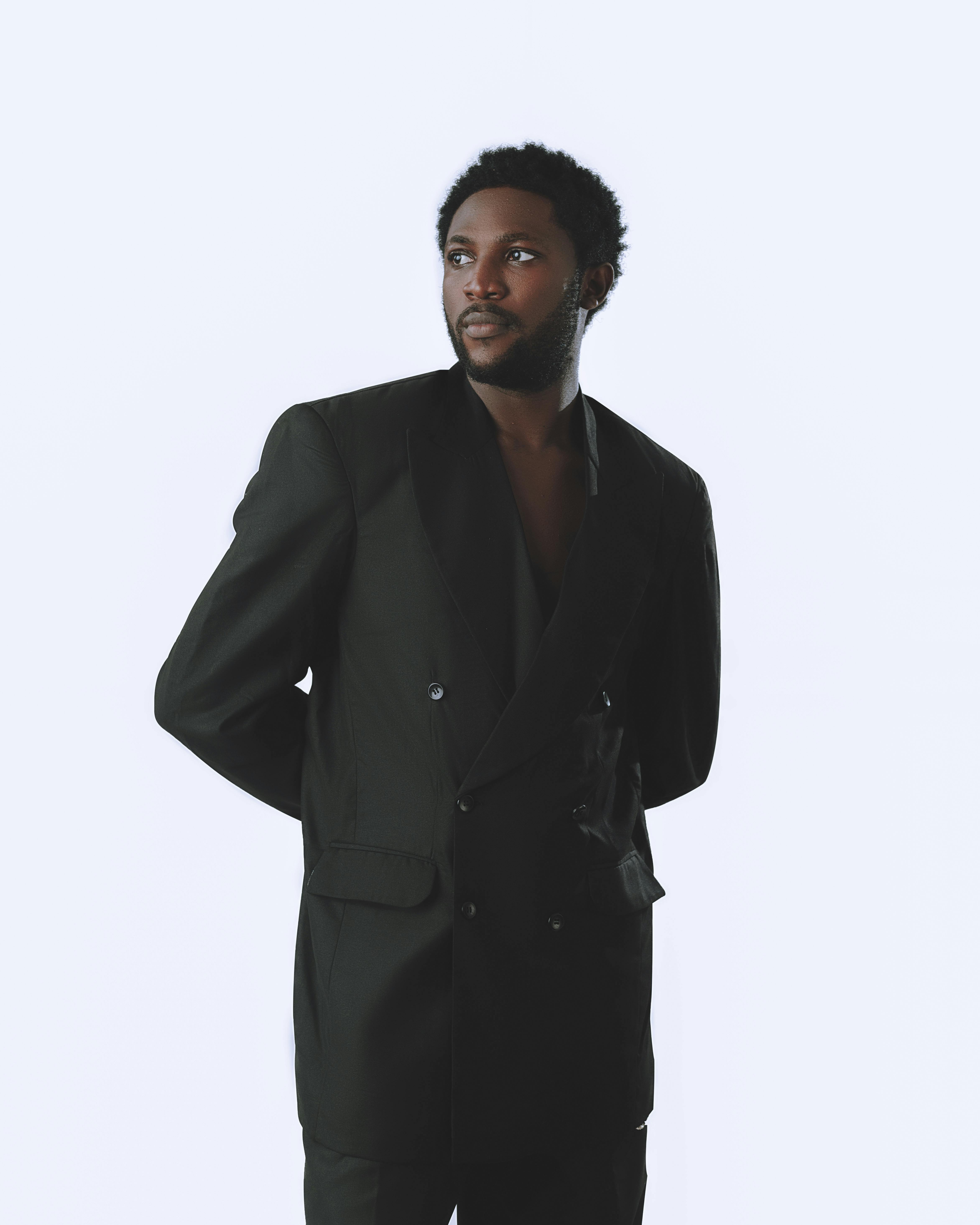 Gratis Ritratto sofisticato di un uomo in abito nero su sfondo neutro. Foto a disposizione