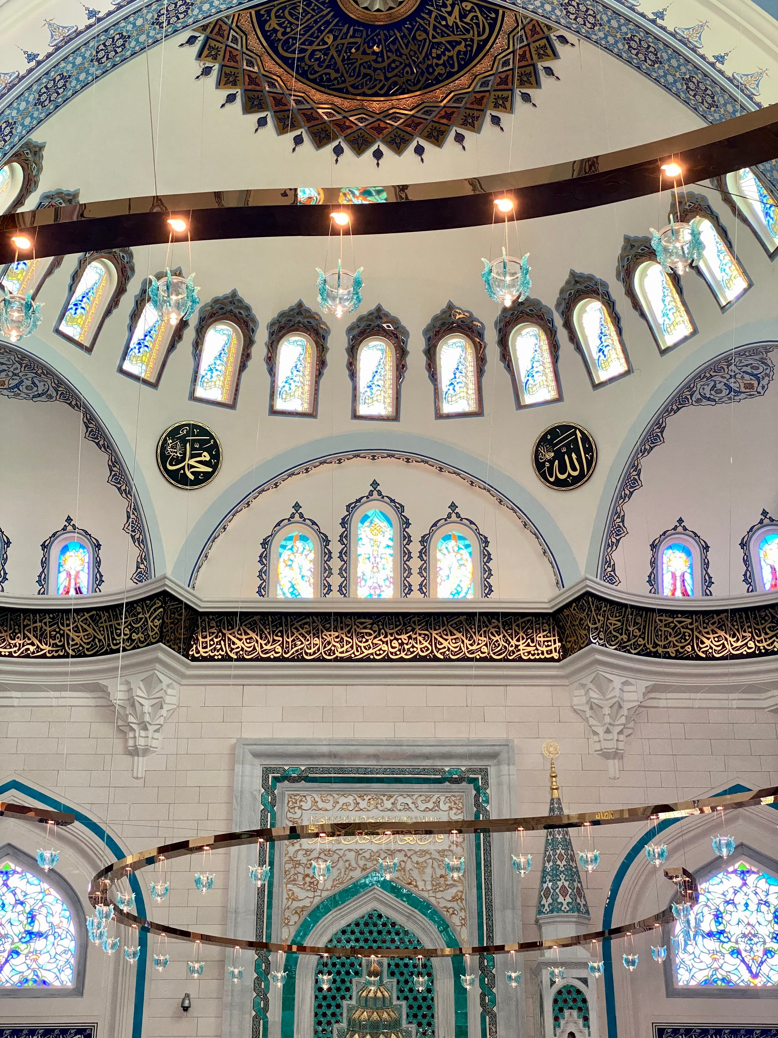 Intricate mosque interior showcasing ornate arches and colorful stained glass windows.