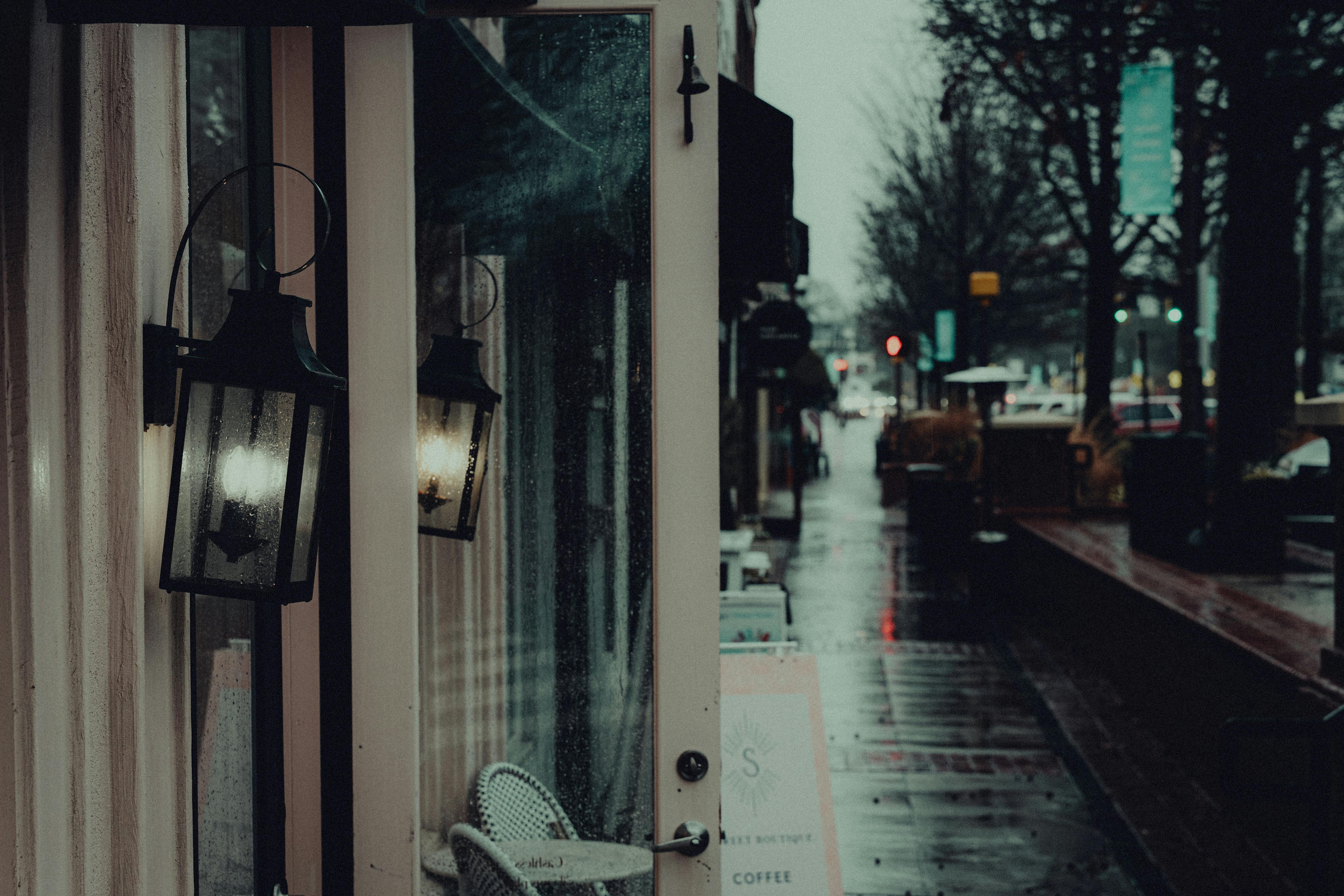 bezplatná Deštivá městská ulice s atmosférickým osvětlením odrážejícím se ve skleněných dveřích. Základová fotografie