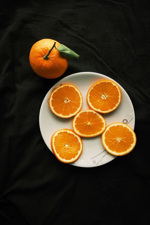 Free Artistic top view of juicy orange slices on white plate against dark background. Stock Photo