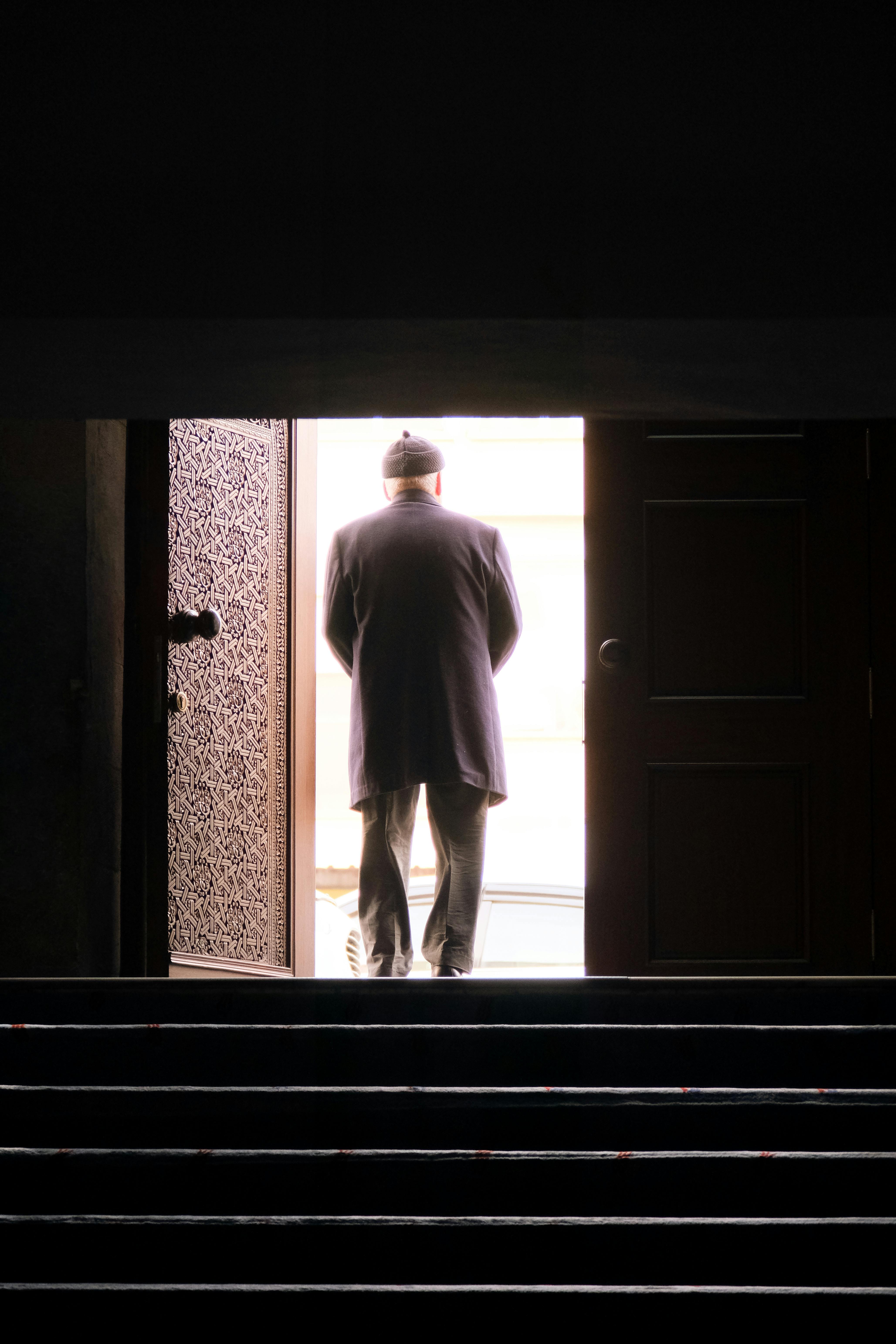 Silhouette of a man leaving an open doorway into the light, creating a dramatic contrast.