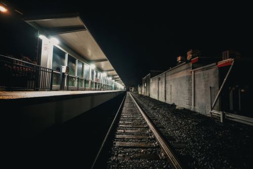 Free Deserted train platform with dim lighting and empty tracks at night. Stock Photo