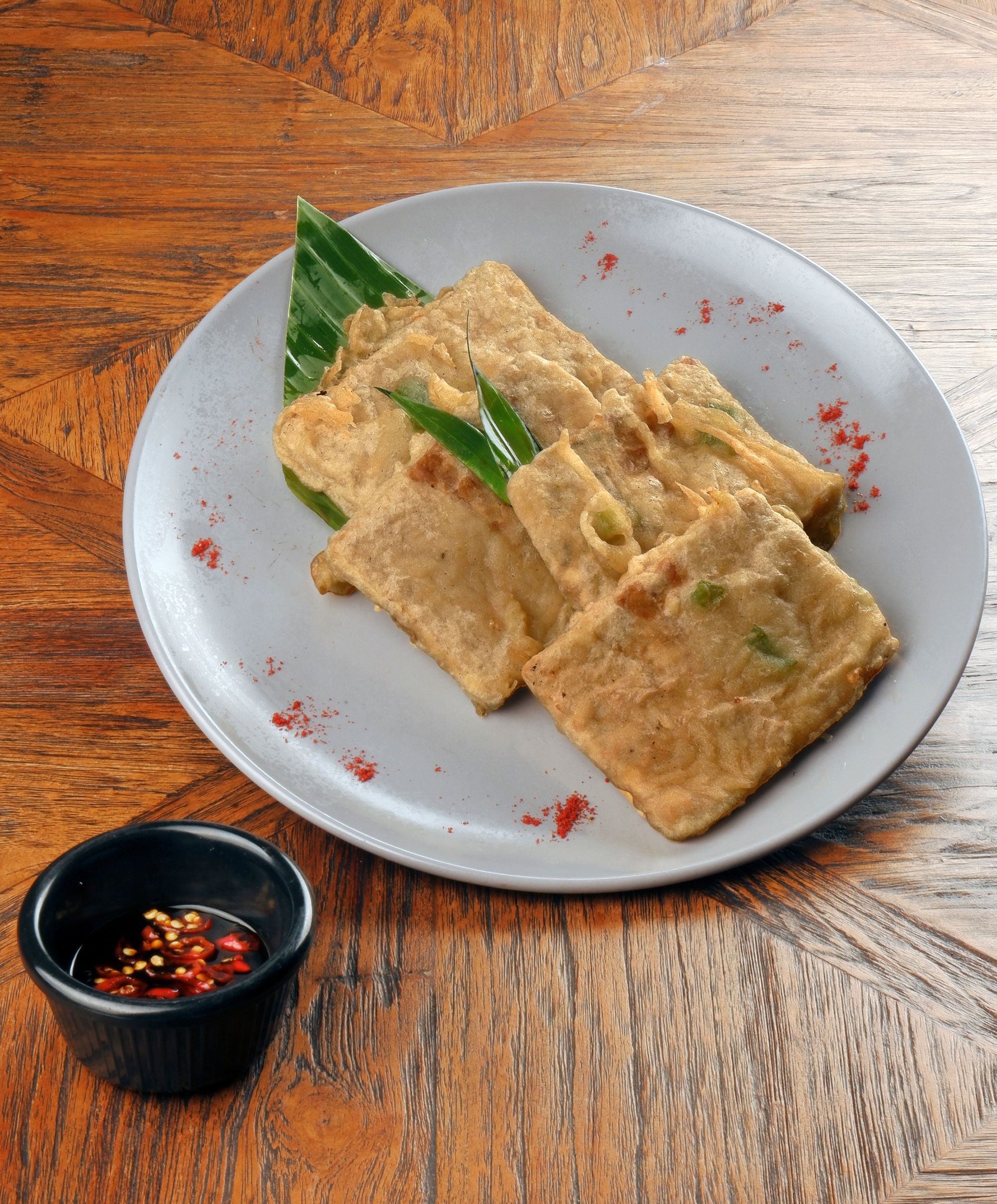 Savor traditional Indonesian tempeh served with spicy chili dip on a wooden table.
