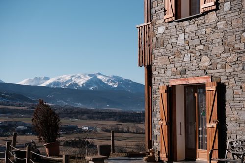 Free Stone house with wooden shutters overlooking snow-capped mountains in a clear winter day. Stock Photo