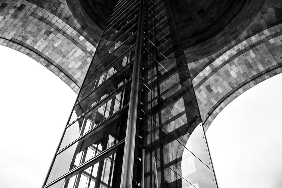 Dramatic perspective of a modern architectural structure featuring glass and stone.