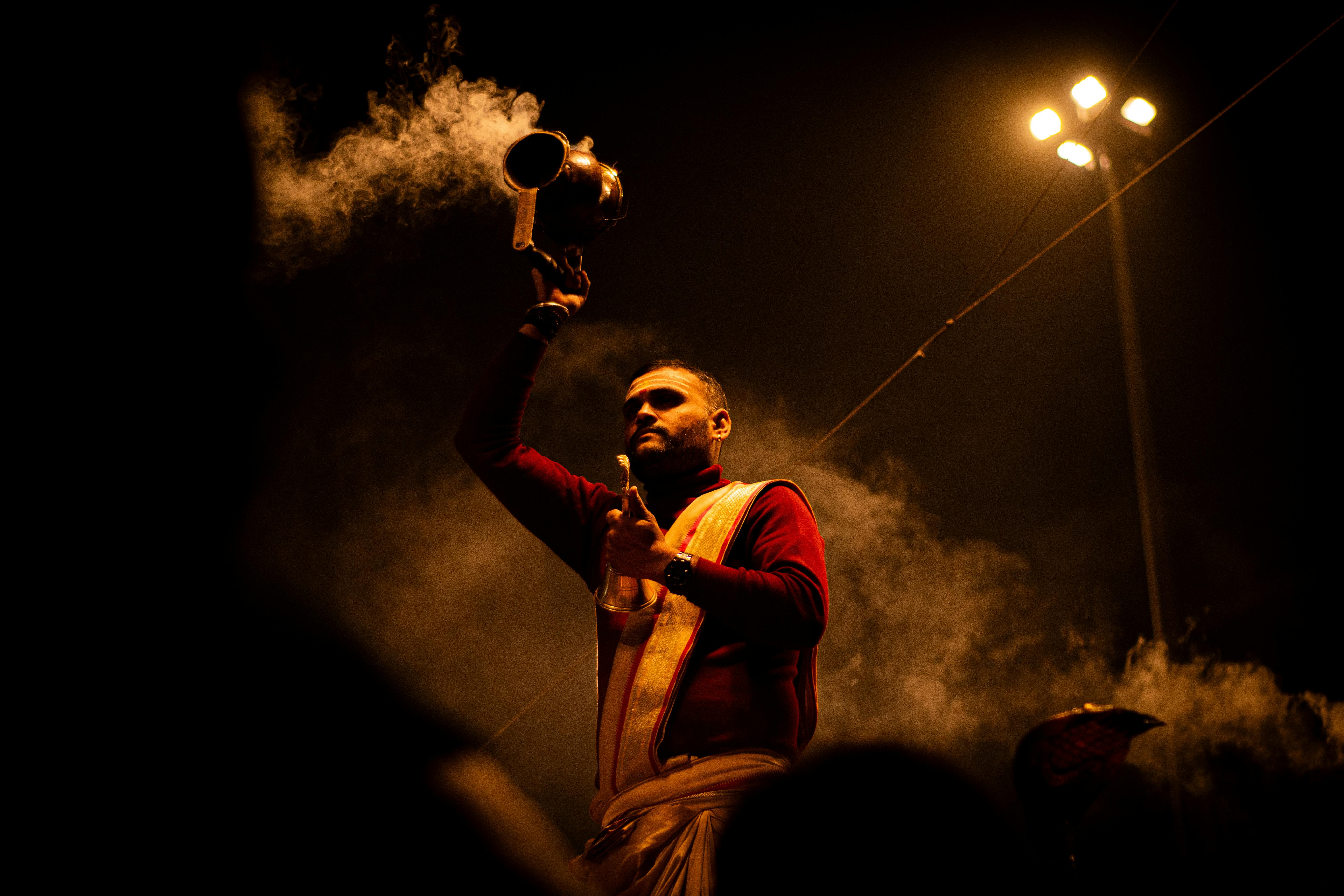 A Hindu priest performs a traditional Ganga Aarti ceremony on the ghats of Varanasi at night.