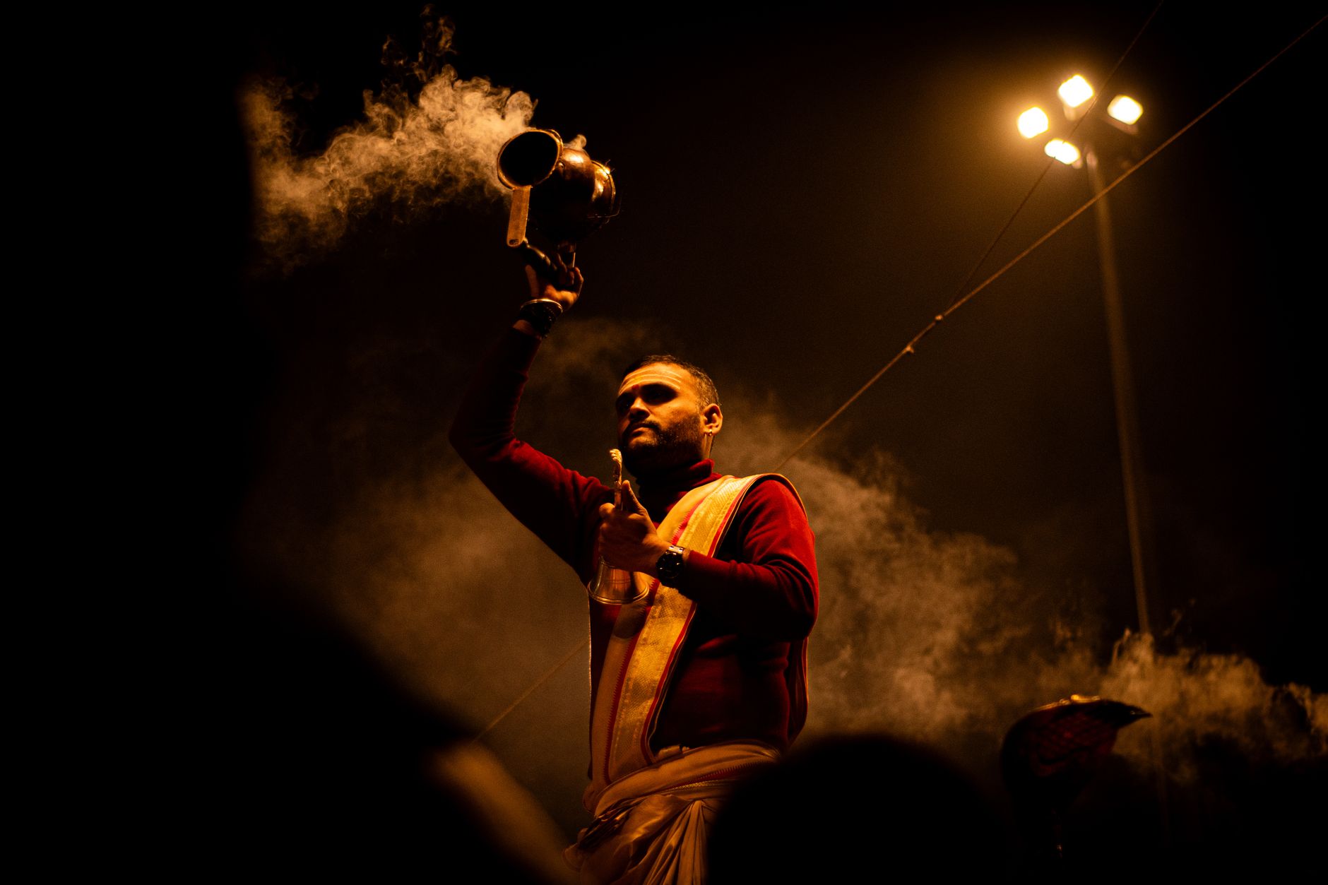 A Hindu priest performs a traditional Ganga Aarti ceremony on the ghats of Varanasi at night.