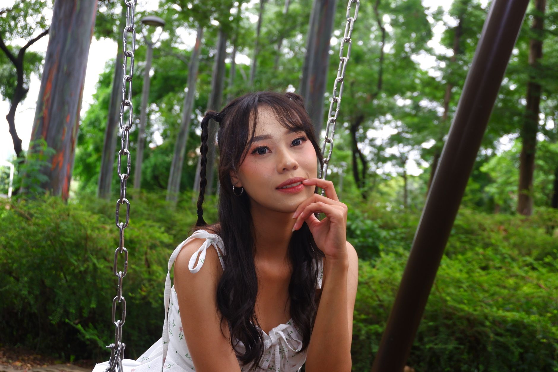 Portrait of a young woman sitting on a swing in a lush green park in Jakarta, Indonesia.