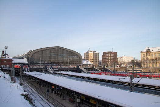 Snowy winter day at Hamburg Central Station with trains and blue sky.