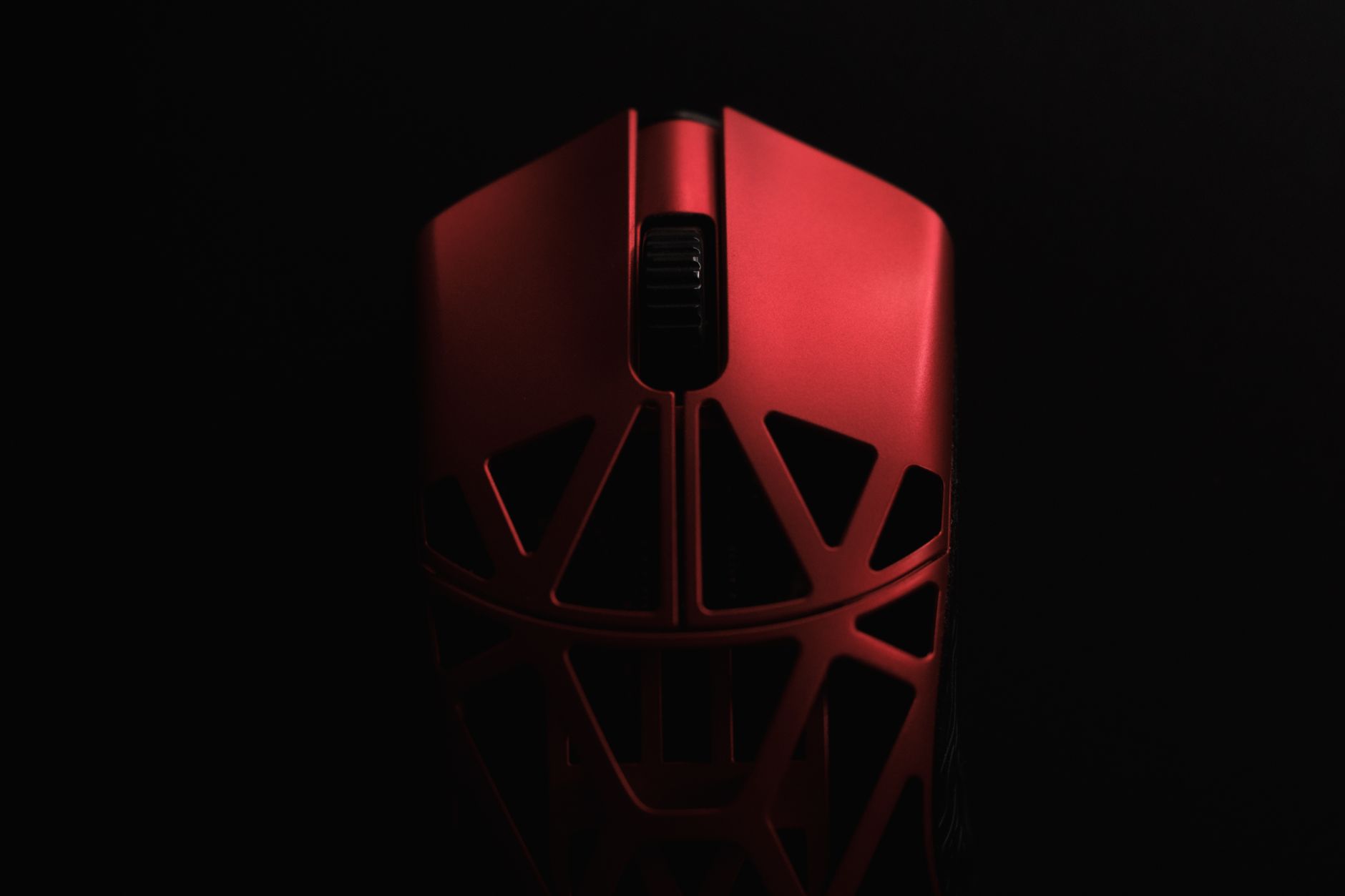 A red gaming mouse with a sleek design and ergonomic features against a dark backdrop.