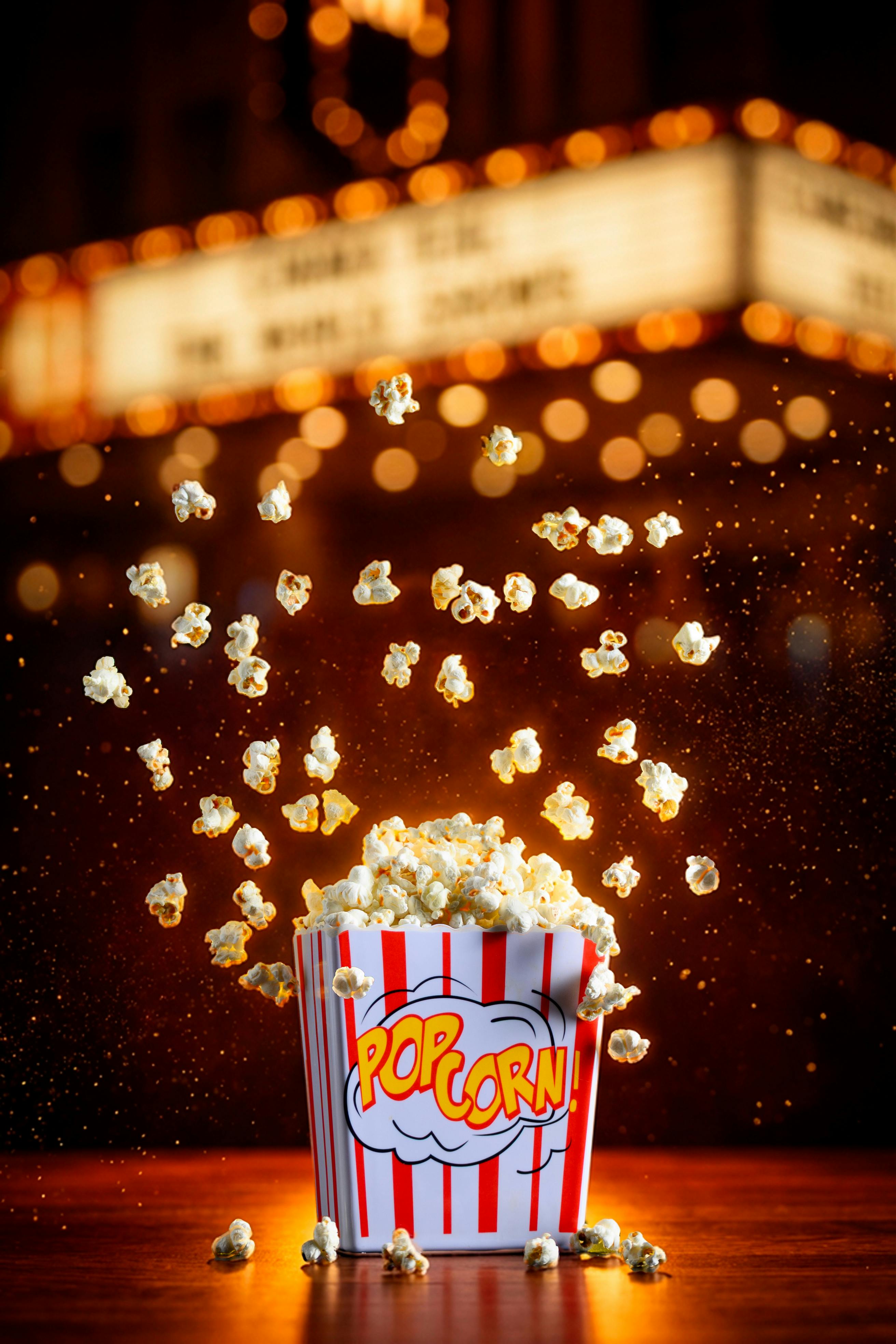 Gratuit Image éclatante de pop-corn jaillissant d'une boîte rayée dans un décor cinématographique. Photos