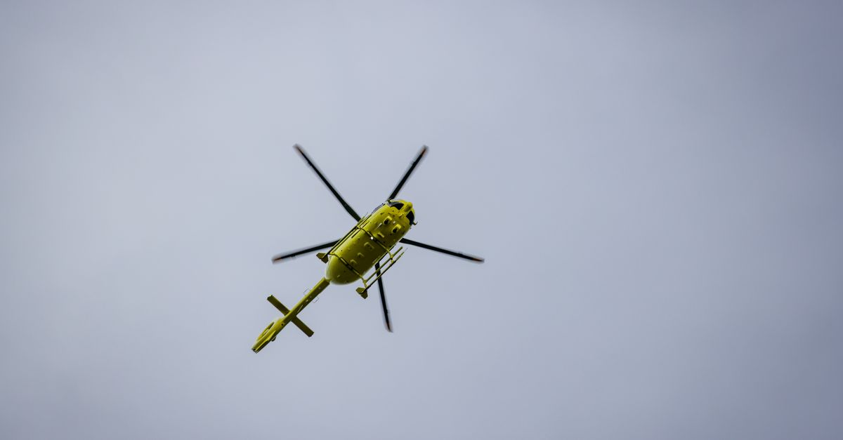 A vibrant yellow helicopter seen flying against a clear blue sky.