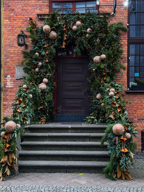 Free Elegant doorway adorned with festive Christmas decorations, lush greenery, and ornaments. Stock Photo