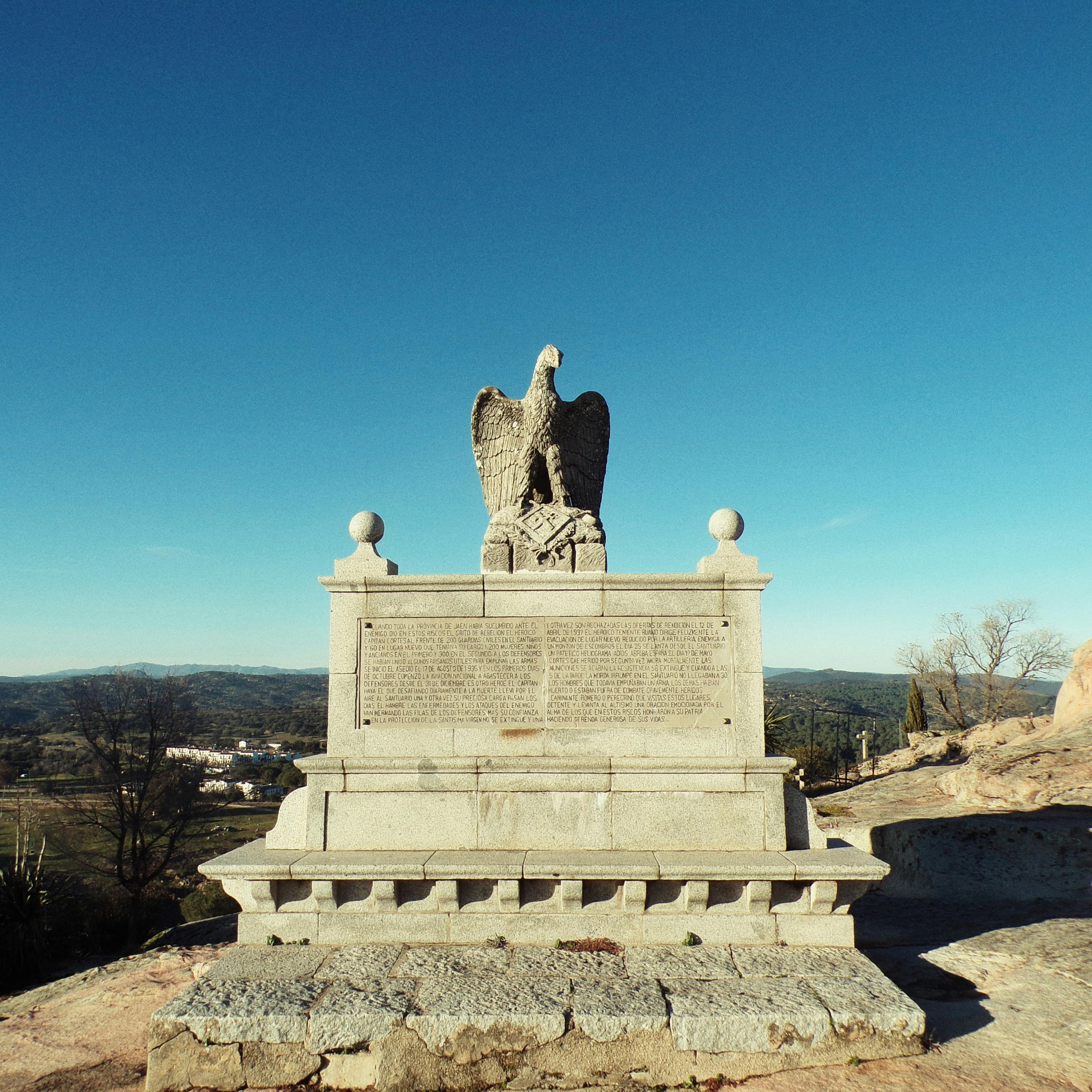 Eagle-topped granite monument under a clear blue sky, depicting a scenic landscape.