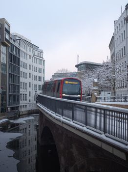 A wintery view of a red train crossing a bridge in snowy Hamburg, Germany.