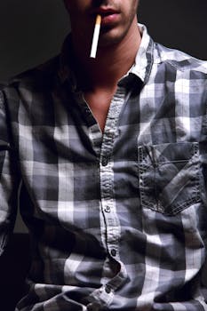 A portrait of a man wearing a checkered shirt with a cigarette in his mouth, exuding a casual vibe.