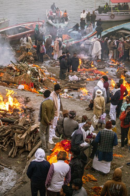 Free A traditional Hindu cremation ceremony taking place on a bustling riverbank in India, showcasing cultural rituals. Stock Photo