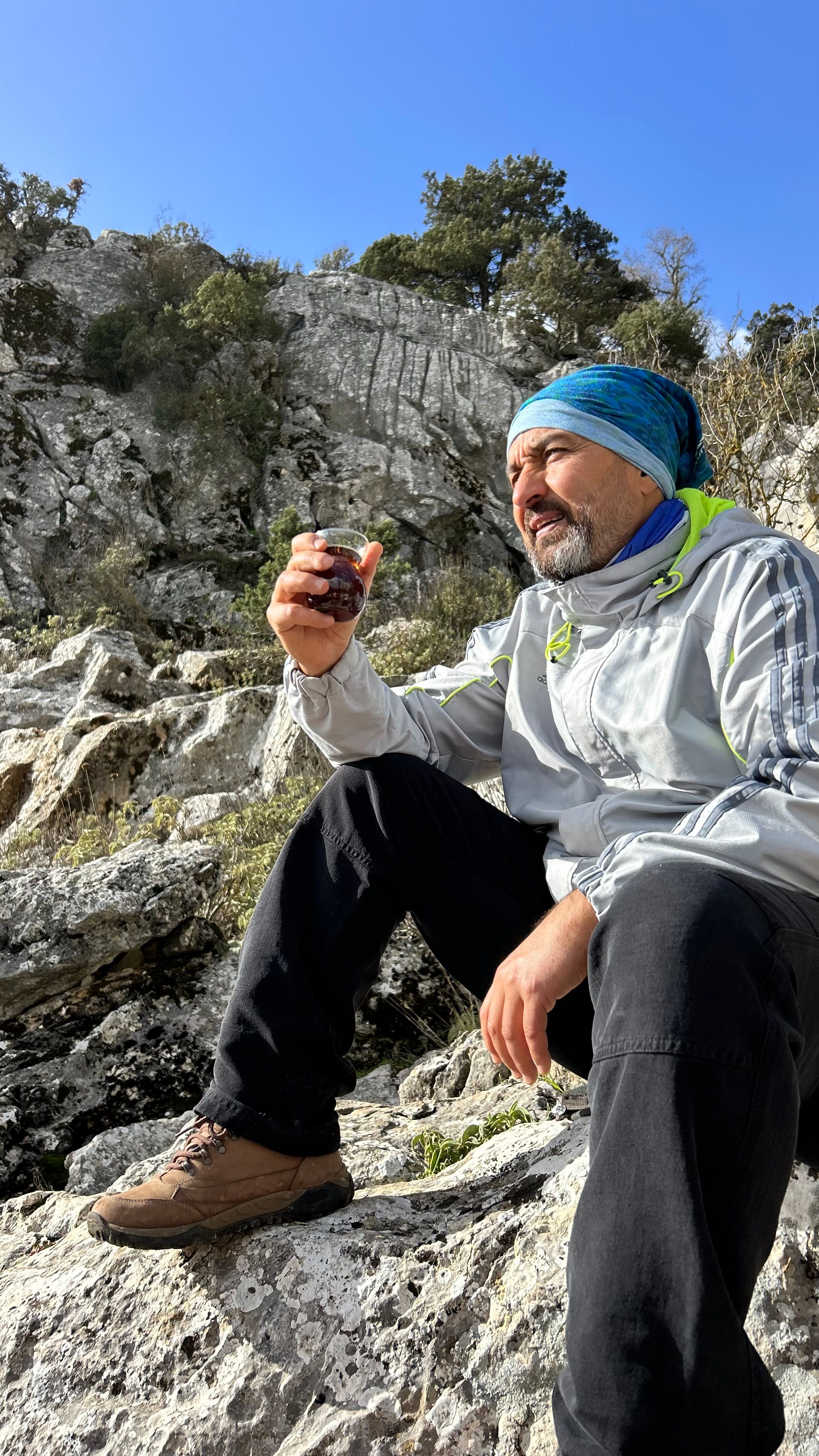 Middle-aged man sitting on rocks outdoors, enjoying scenic view. - shilajit tips for wellness