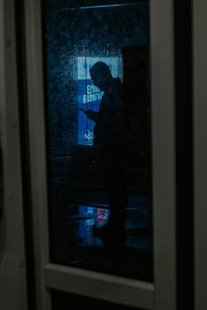 Moody silhouette through a rainy window in İstanbul, capturing a contemplative night scene.