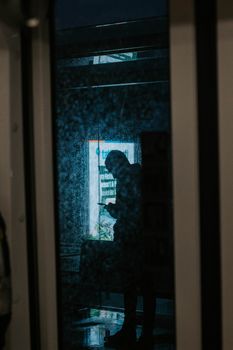 A silhouette of a person using their phone, reflected in a rainy window in Istanbul.