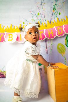 Cute baby in a white lace dress during a birthday celebration.