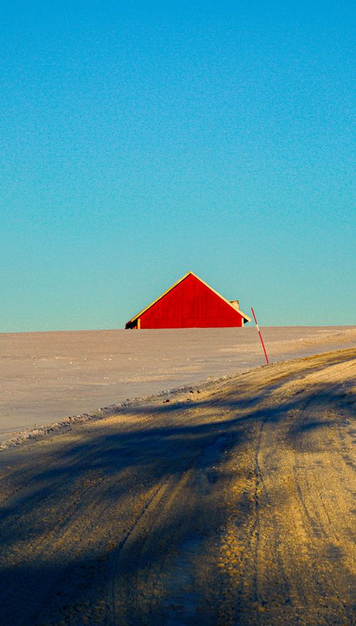 Free A vibrant red barn contrasts against a snowy winter landscape in Gränna, Sweden. Stock Photo