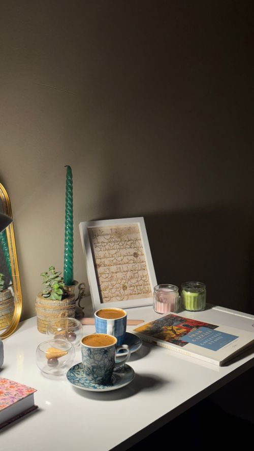 Free Elegantly arranged home office desk with coffee, candles, books, and plants. Stock Photo