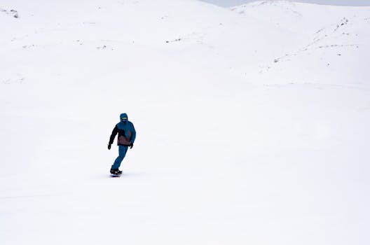 A snowboarder in blue gear gliding across a vast snowy landscape, showcasing winter adventure.