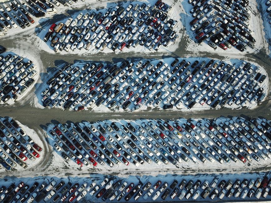 Aerial shot of cars parked in a snow-covered lot, showcasing an organized layout during winter.