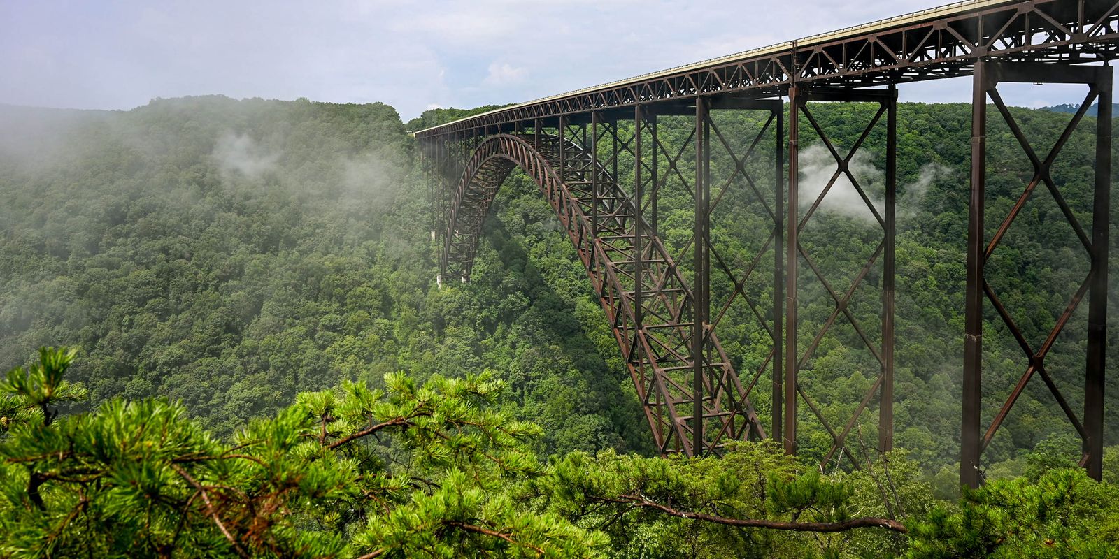 The New River Gorge Bridge surrounded by green forest and mist