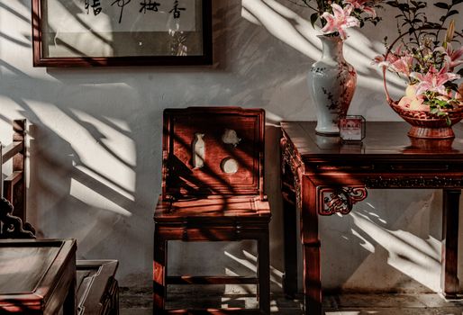 Warm sunlight on vintage wooden furniture and floral decor in an elegant interior setting.