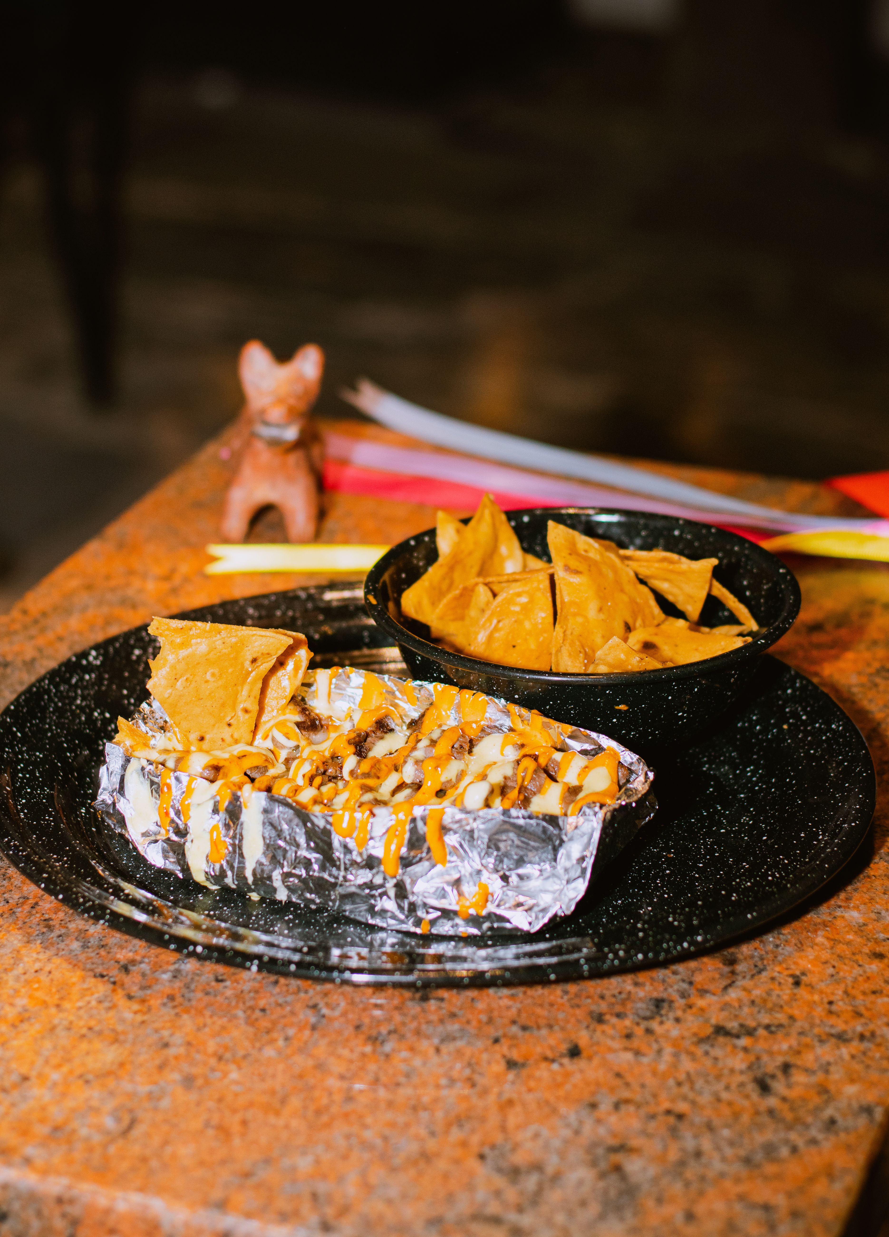 Plate of nachos drizzled with cheese sauce on a table, perfect for a casual dining setting.