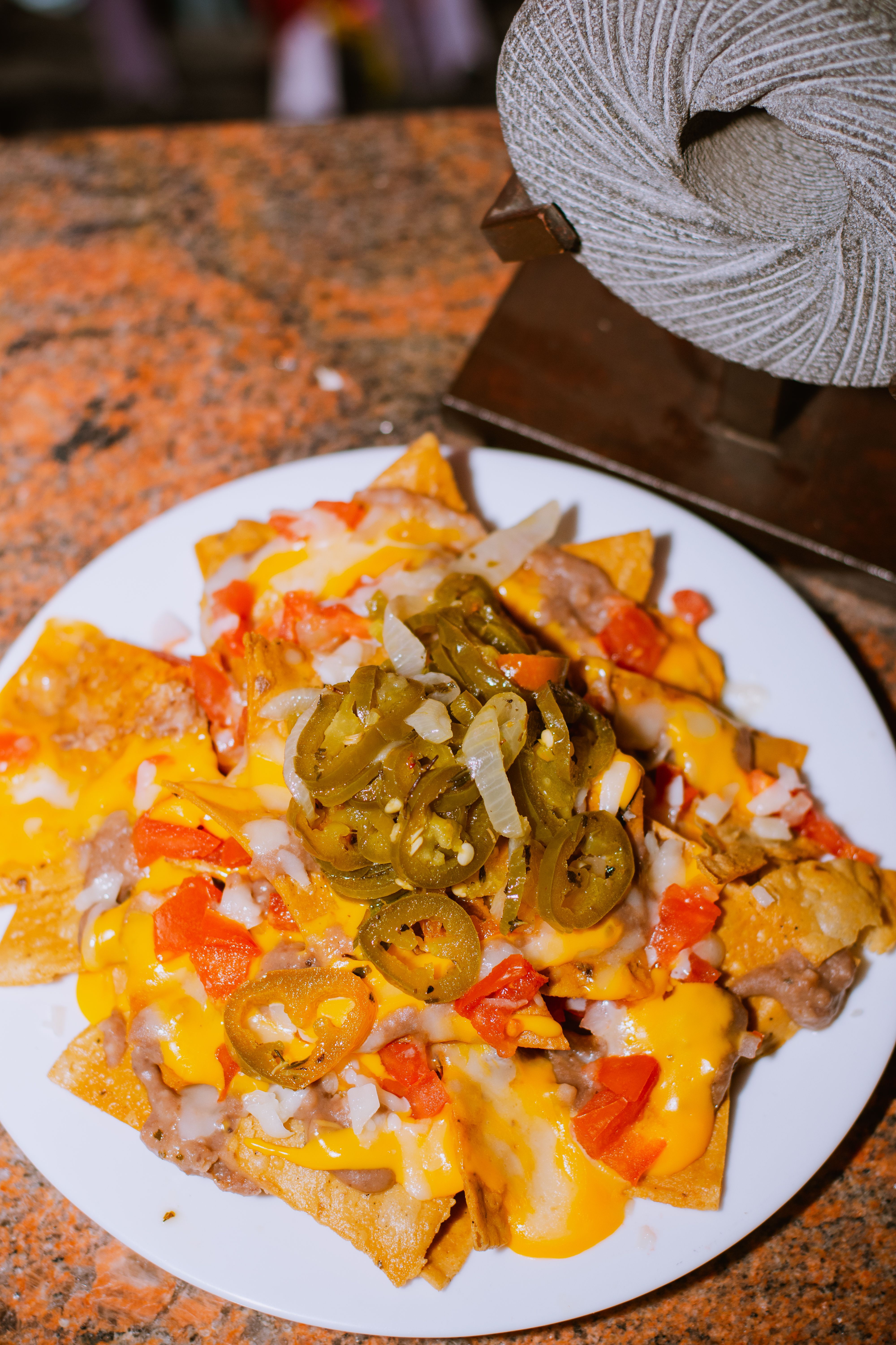Appetizing plate of nachos topped with melted cheese, jalapenos, and diced tomatoes.