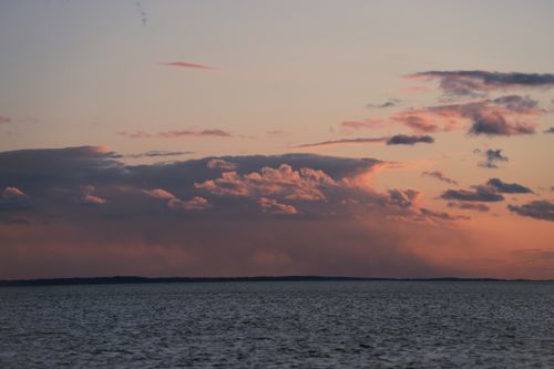 Free Calming ocean view at sunset with dramatic clouds and vibrant colors in the sky. Stock Photo