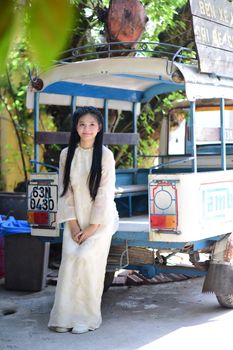 Young woman in traditional clothing poses with a vintage rickshaw, creating a nostalgic outdoor scene.