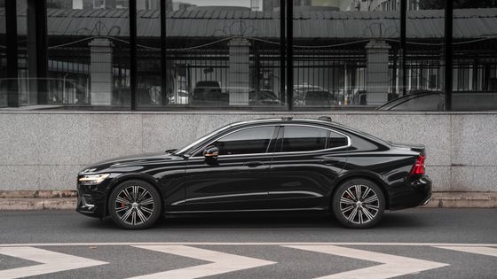 Black saloon in side profile beside a pale stone wall. Photo by Oli Liao on Pexels